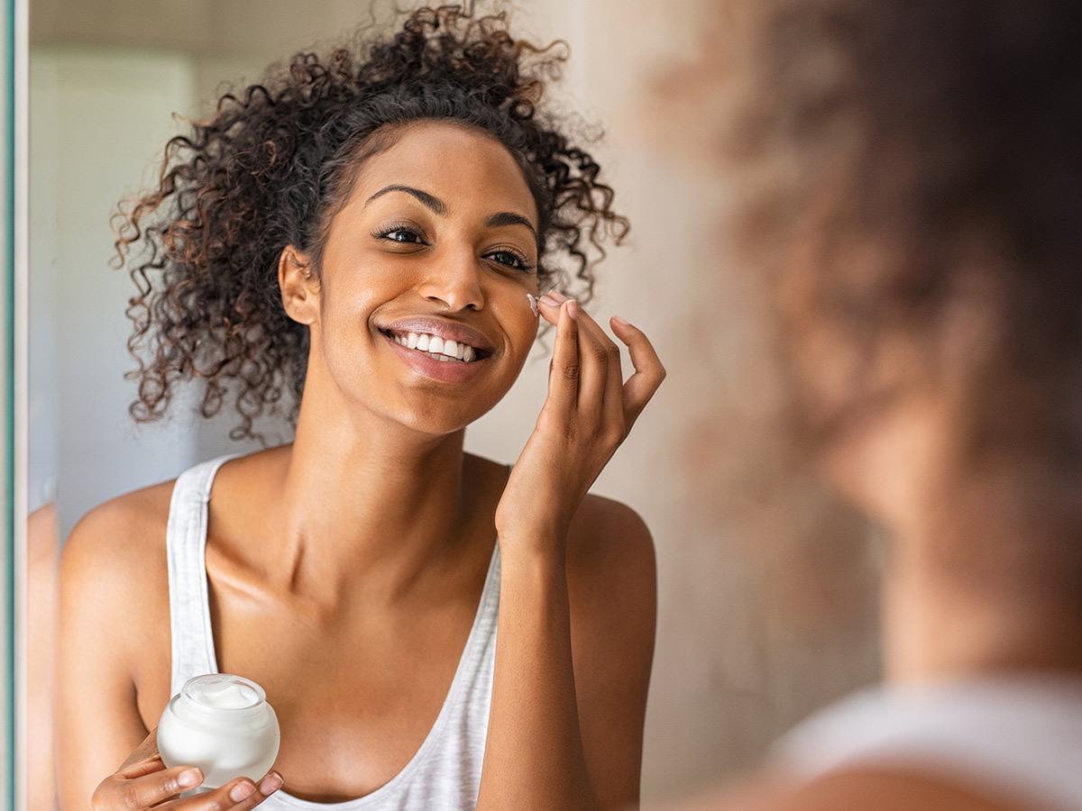 Woman applying lotion to her face in the morning