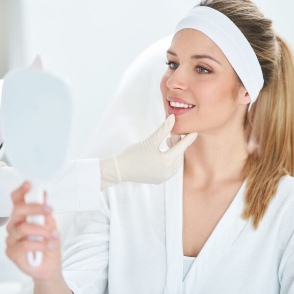 Patient looking at their reflection as skincare specialist performs assessment