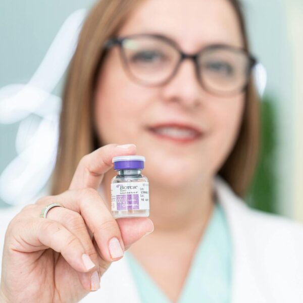 a woman holding a vile of botox fluid