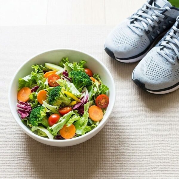 A bright photograph of a fresh salad bowl next to athletic sneakers on a simple mat, representing healthy lifestyle choices.